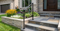 handrail is build with tube clamps.home entrance featuring slate steps, a black handrail, and vibrant flower beds.