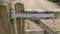 Zinc-plated gate band hinge bolted across the top rail of a wooden gate, hung on a pin at the gate post
