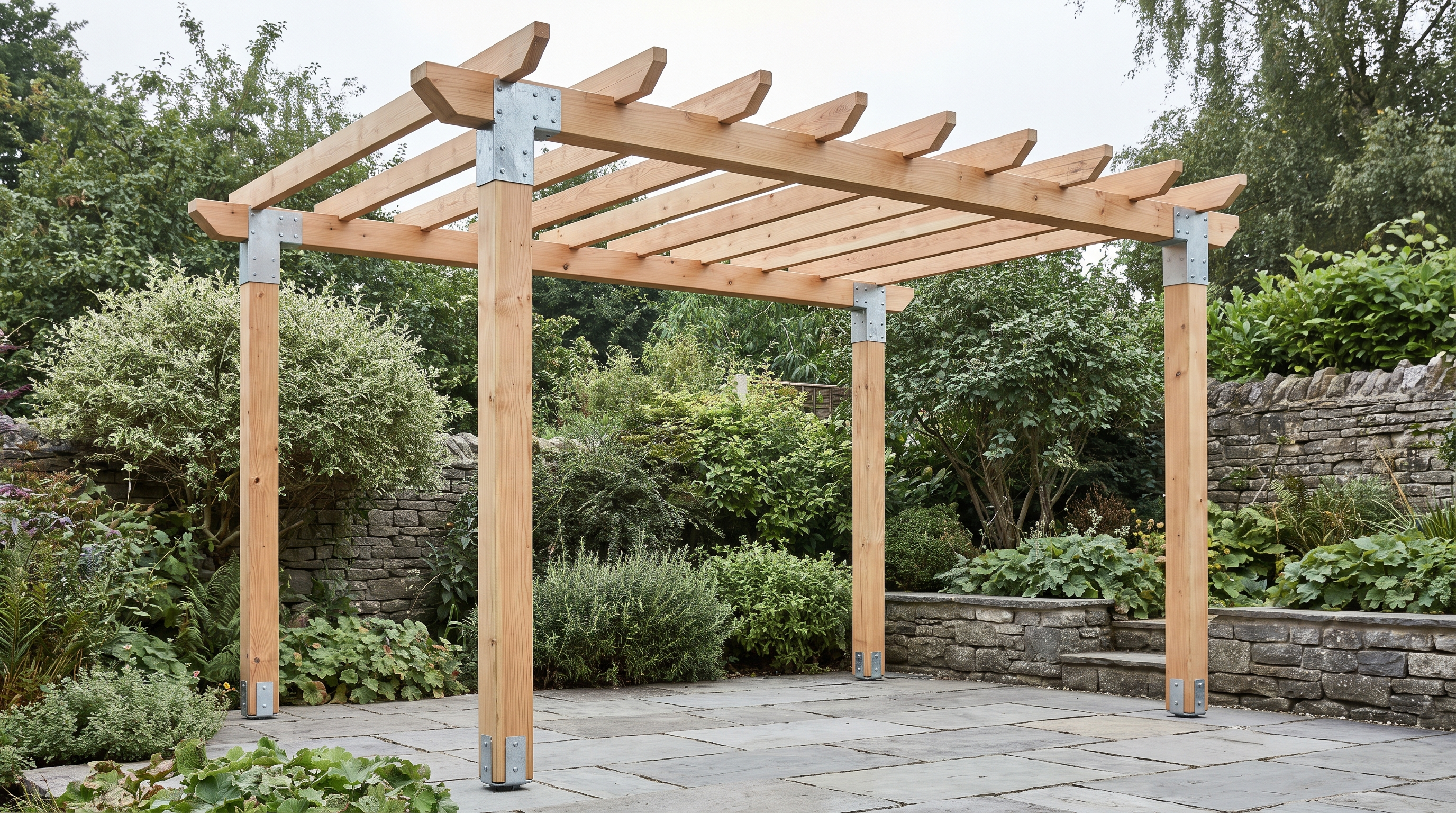 Timber pergola with galvanised steel corner connectors at the post tops and bolt-down post shoes at the base, on a paved garden patio.